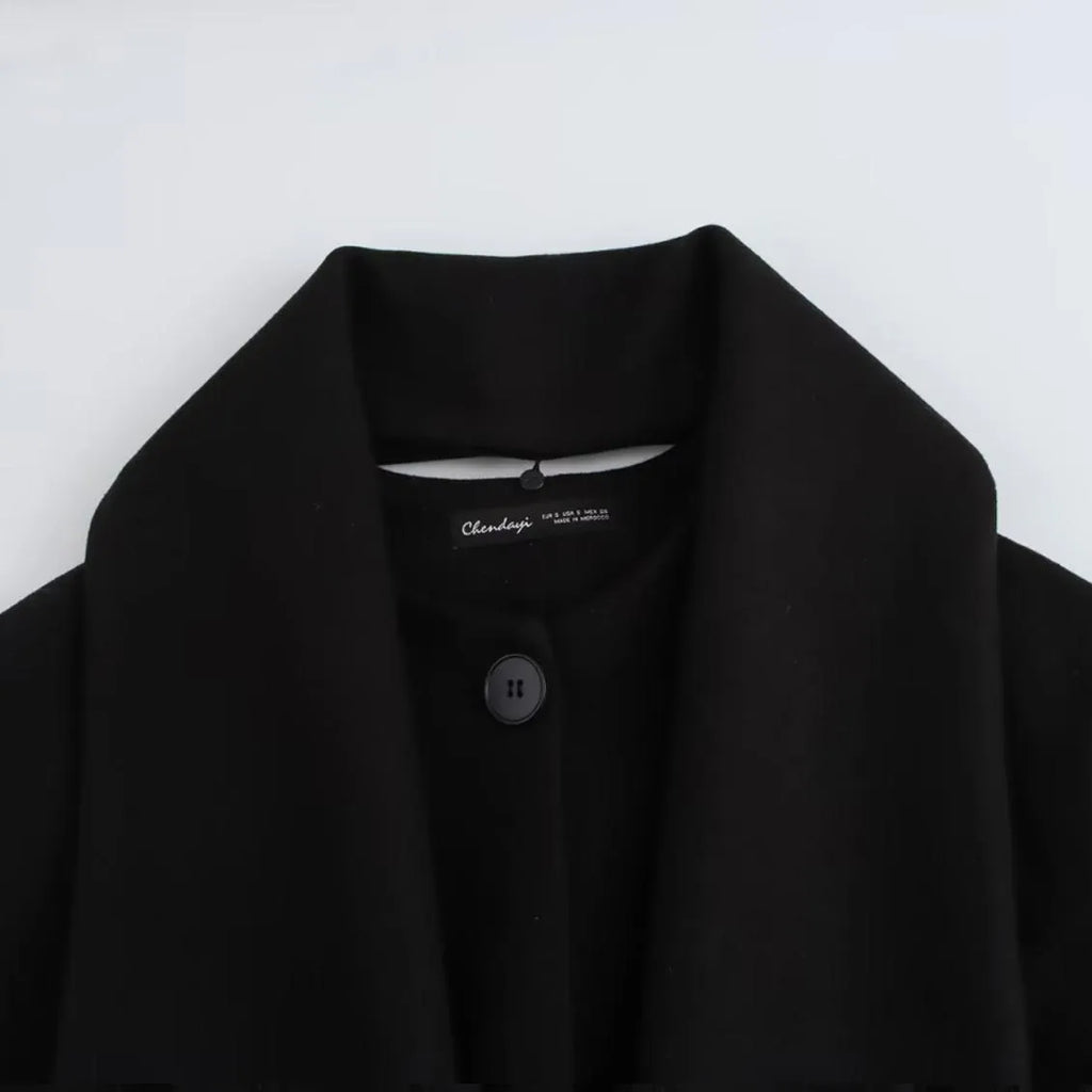Women's long black polyester overcoat with artificial fur collar and pockets, showing extended length.