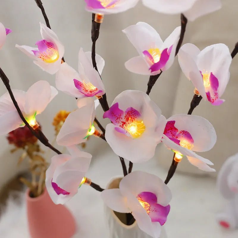 Pink LED phalaenopsis orchid branch decorative light on a table, 65cm long with warm white lights.
