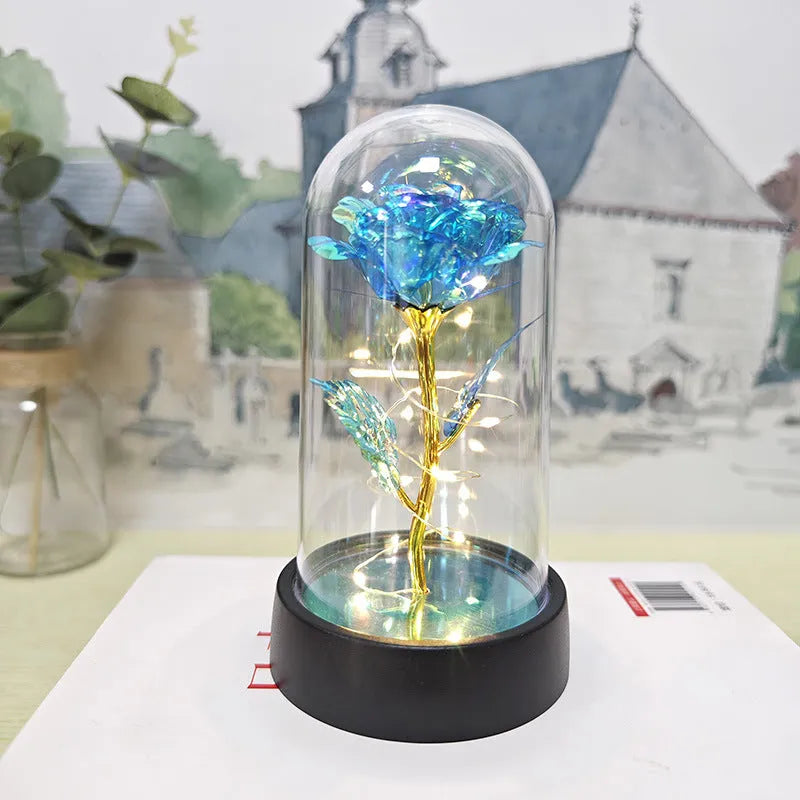 Small decorative night lamp with glass cover and plastic flowers, showing coloured light illumination.