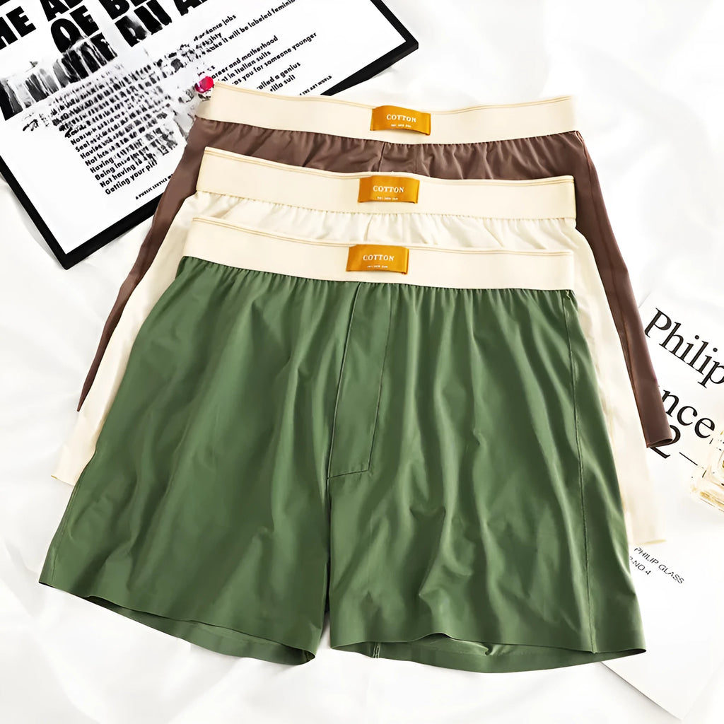 Three pairs of men's solid colour ice silk briefs on a grey background.