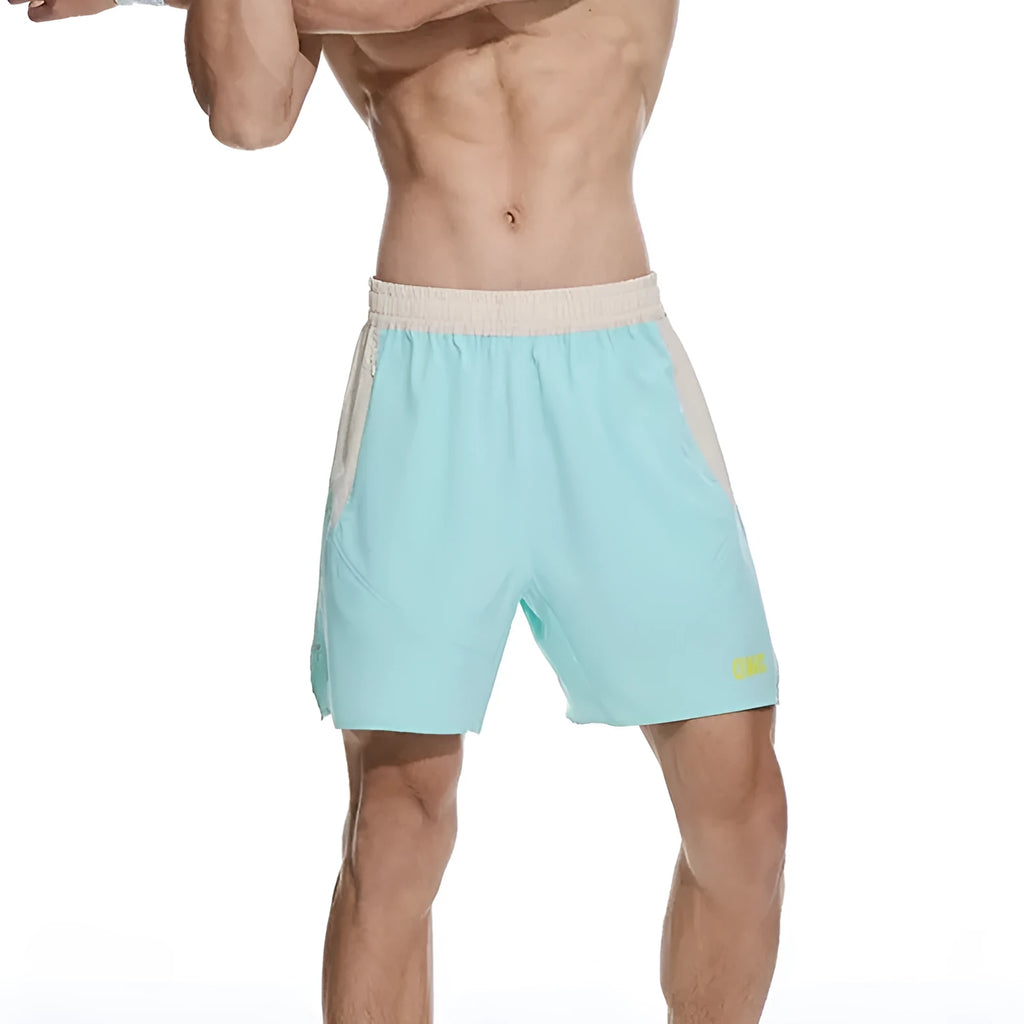 Men's loose grey workout shorts with elastic waist and lace-up fly on a gym floor.