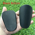 Extra small plastic football shin guards in black and white, measuring 8x5cm