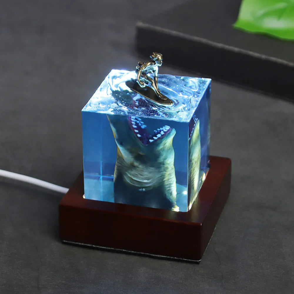 Clear epoxy resin night light ornament with a shark surfer scene inside, shown in 5cm and 8cm sizes.