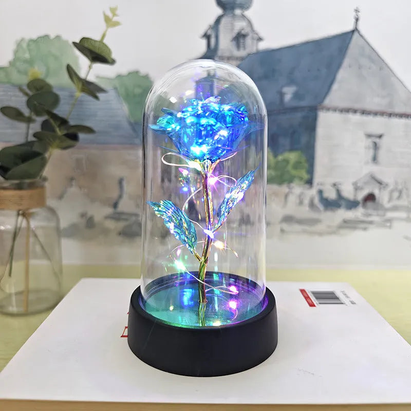 Small decorative night lamp with glass cover and plastic flowers, showing coloured light illumination.