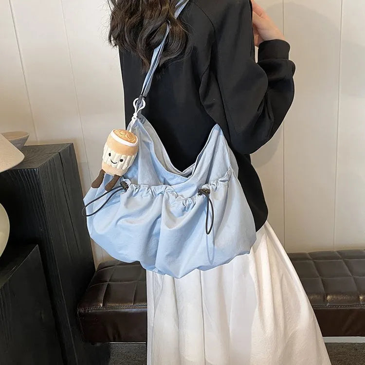 Green pleated folding crossbody student bag with a front split pocket and long strap.