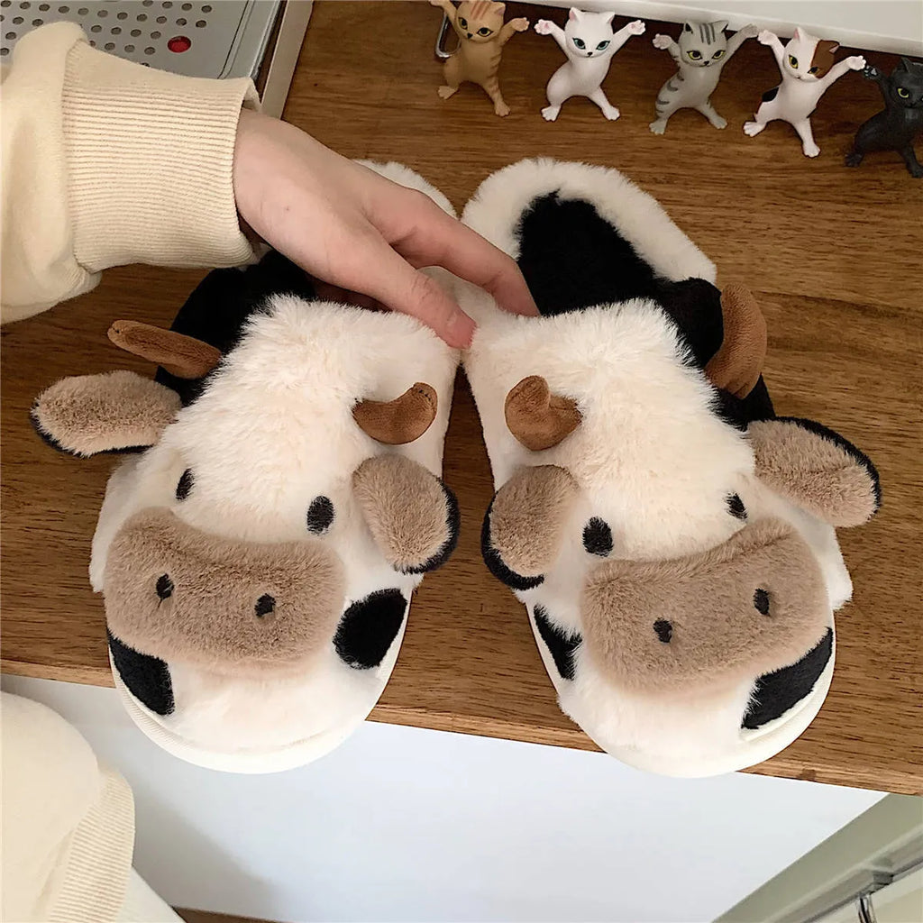 White and coffee coloured cow-themed plush slippers for women with a textured non-slip sole.