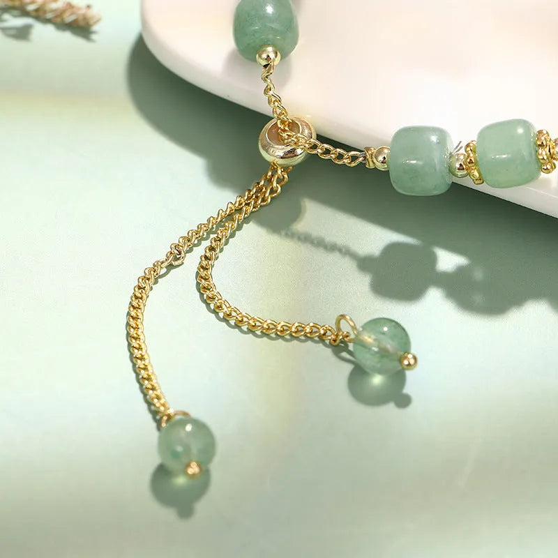 Green aventurine and strawberry quartz rabbit charm bracelet on a copper and gold chain.