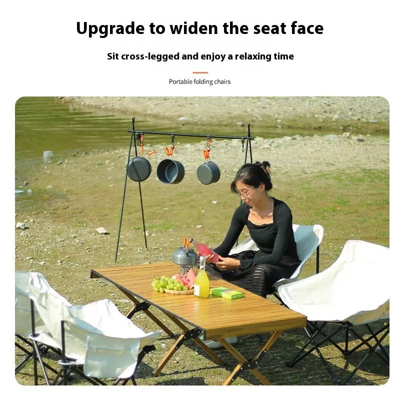Beige folding camping chair with reclined back and steel frame on grass.
