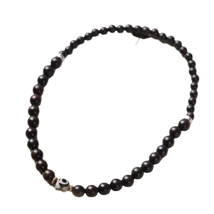Dark ebony wood bracelet with 8mm beads in a two-circle Tibetan style on a wrist.