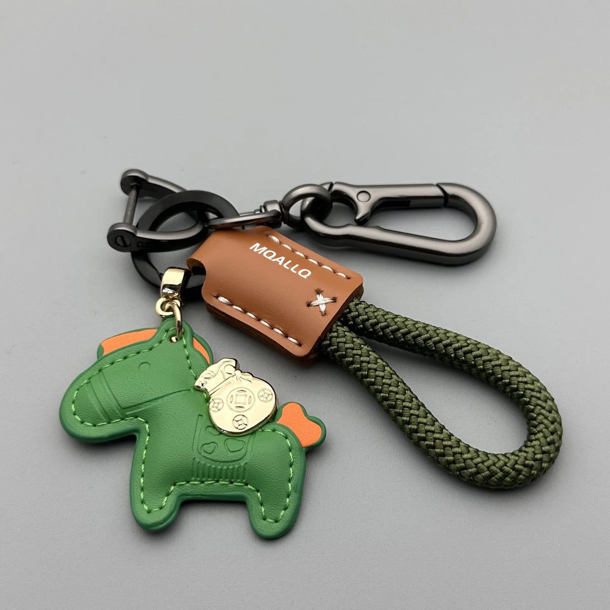 Handmade brown cowhide leather key ring with a gold-toned zinc alloy pony buckle and a green plaited flannelette rope.