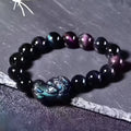 Natural ice colour eye obsidian crystal bracelet on a wrist, showing polished beads on an elasticated band.