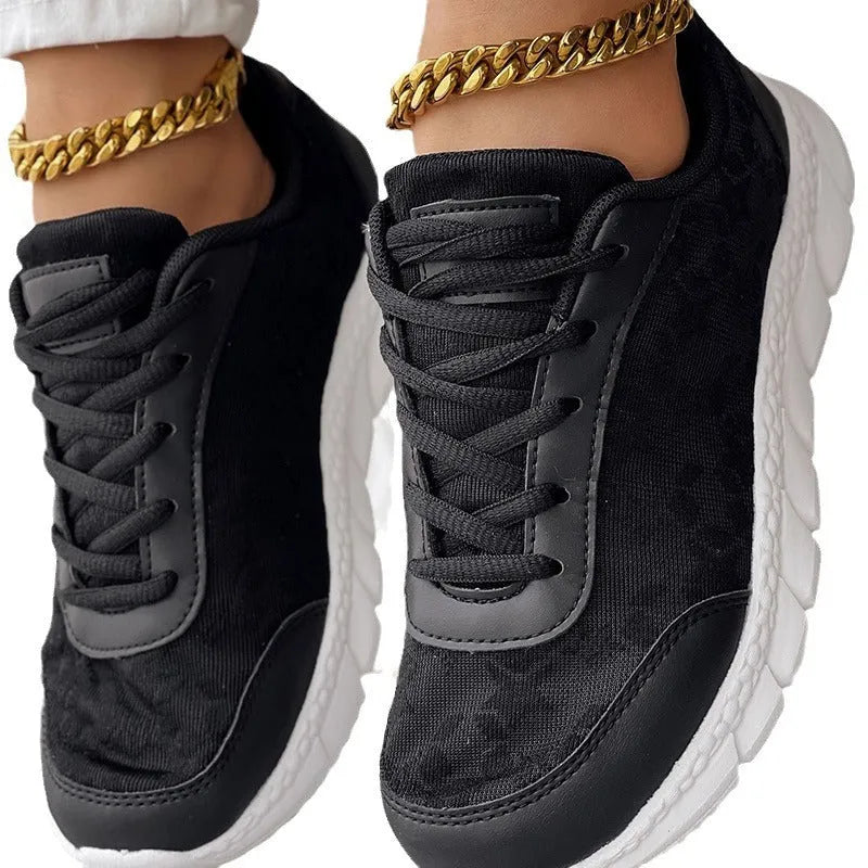 Women's white canvas sports shoes with flat heel and round toe on a plain background.