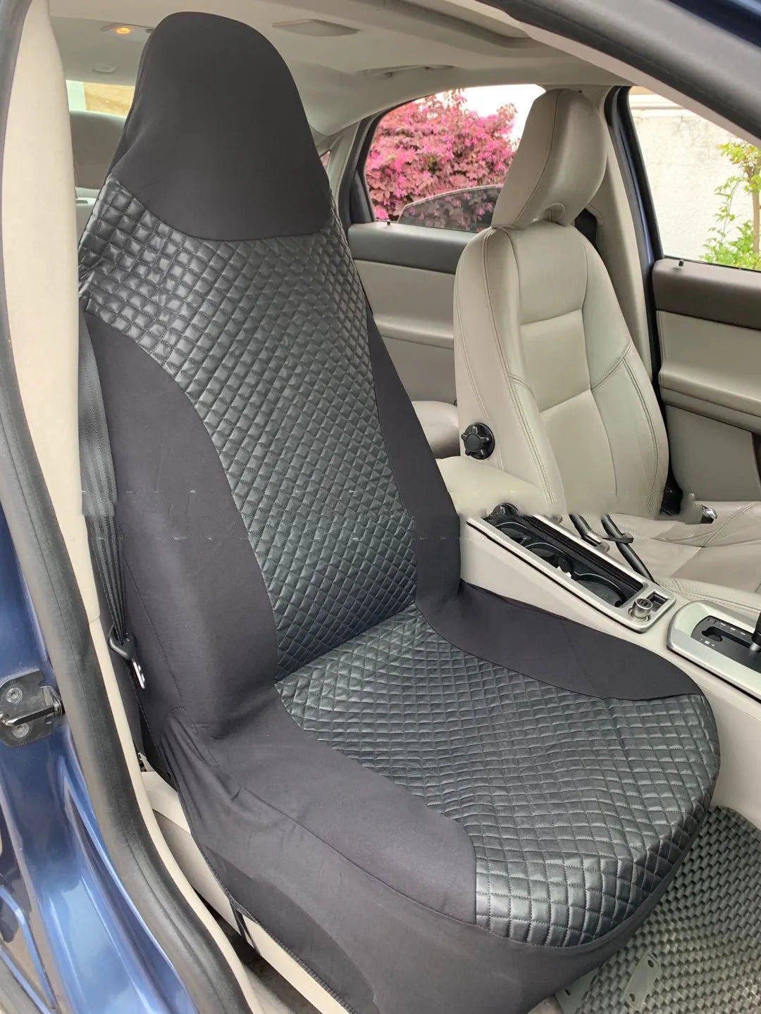 Black quilted car seat cover made of PU and polyester fabric with plastic hooks.