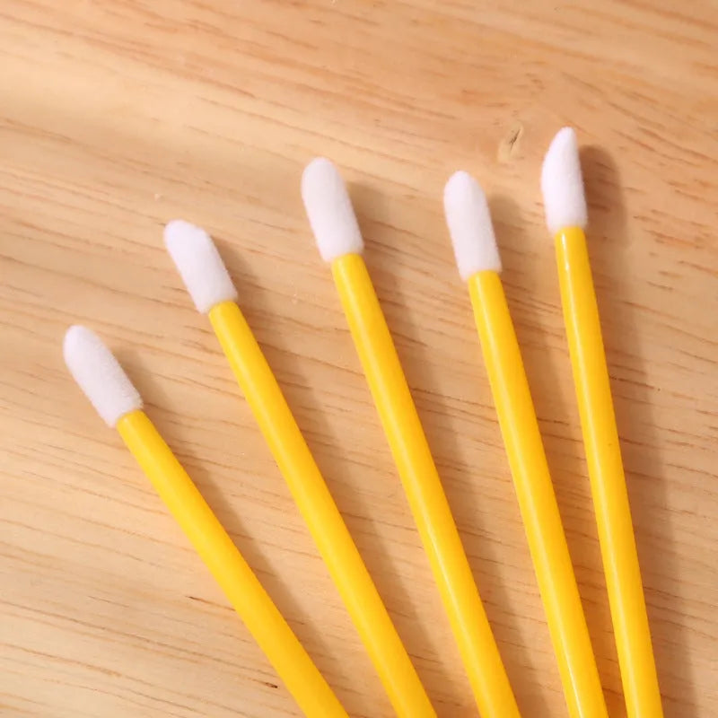 Pack of multi-coloured disposable lip brushes with soft flocked heads on a black handle.