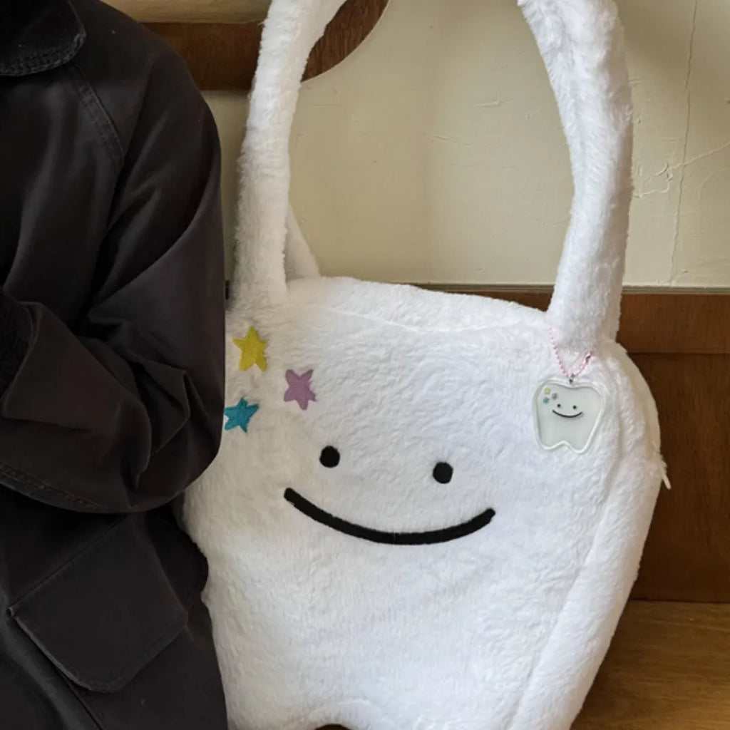 White plush tote bag with a cute teeth pattern, showing the shoulder strap and zipper closure
