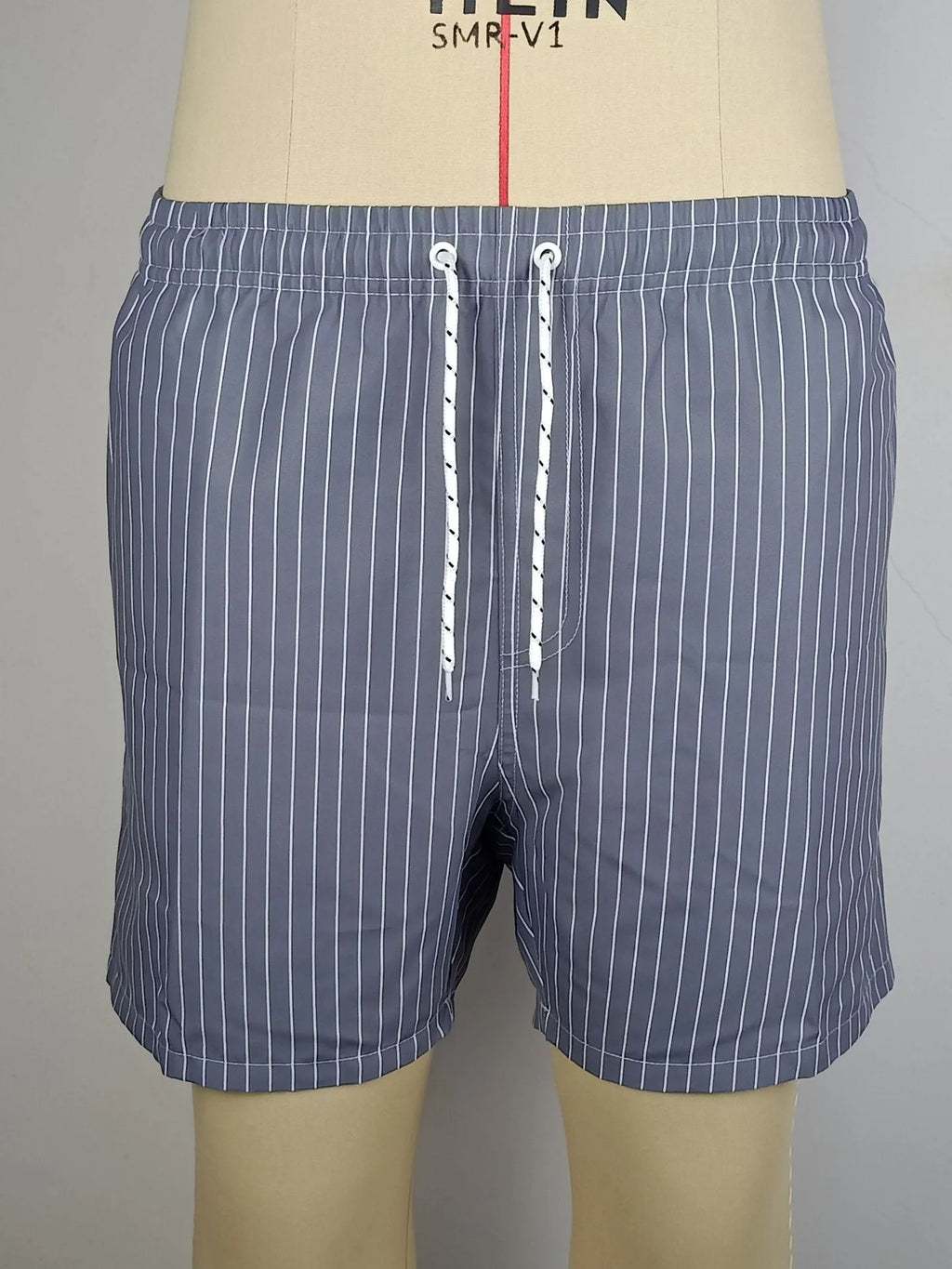 Man or woman wearing striped polyester shorts in navy blue, straight leg style, for beachwear.
