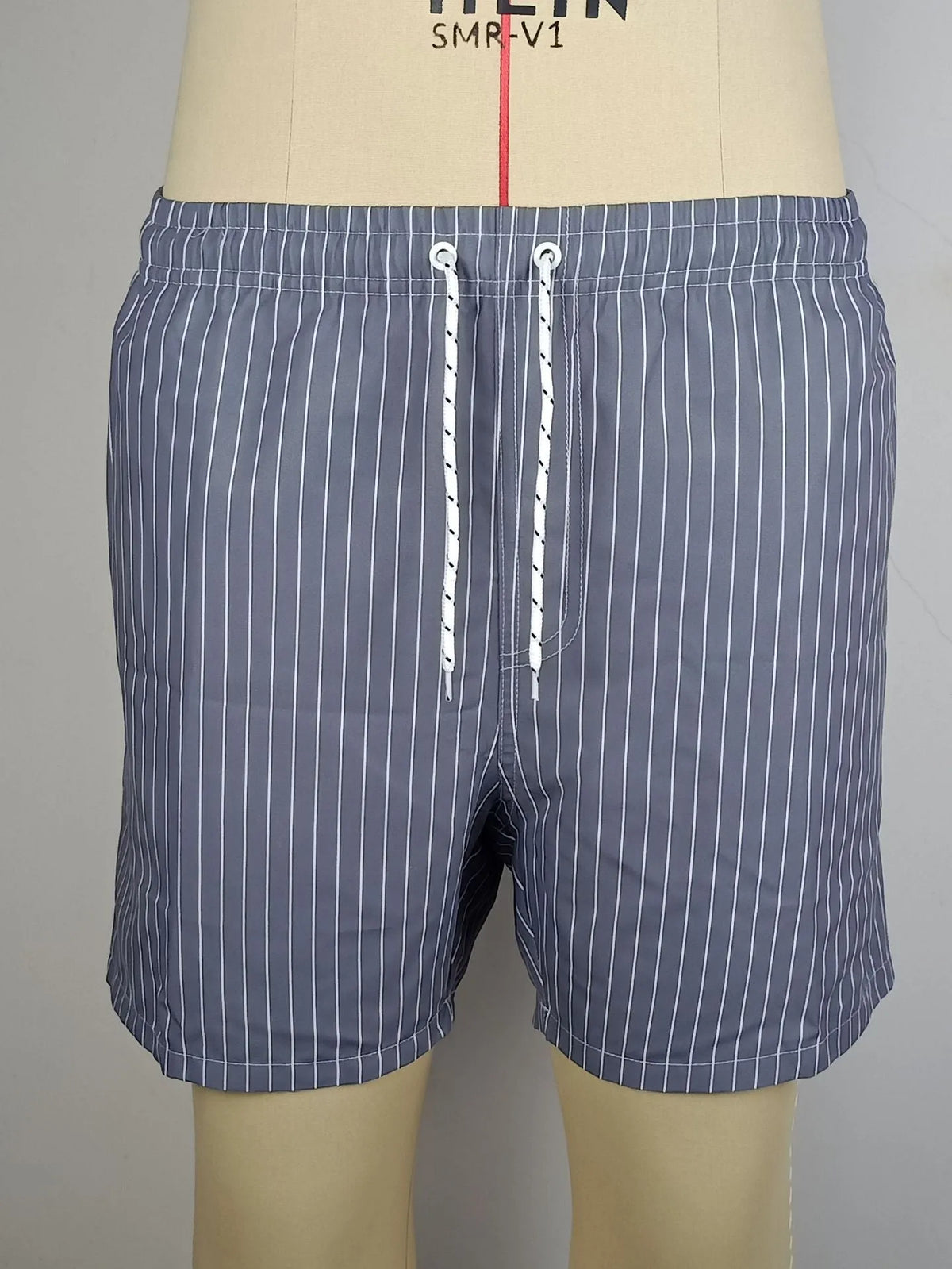 Man or woman wearing striped polyester shorts in navy blue, straight leg style, for beachwear.