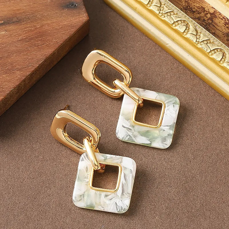 Pair of hollow square earrings with bevelled corners in a metallic finish, shown on a white background.
