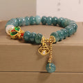 Close-up of a women's bracelet with blue water jade abacus beads, white agate, alloy inlay, and a butterfly clasp.
