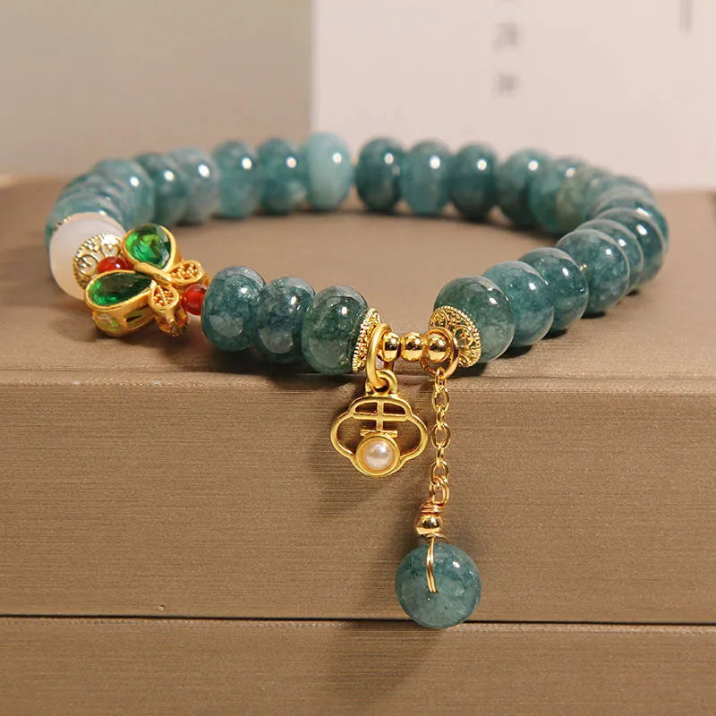 Close-up of a women's bracelet with blue water jade abacus beads, white agate, alloy inlay, and a butterfly clasp.