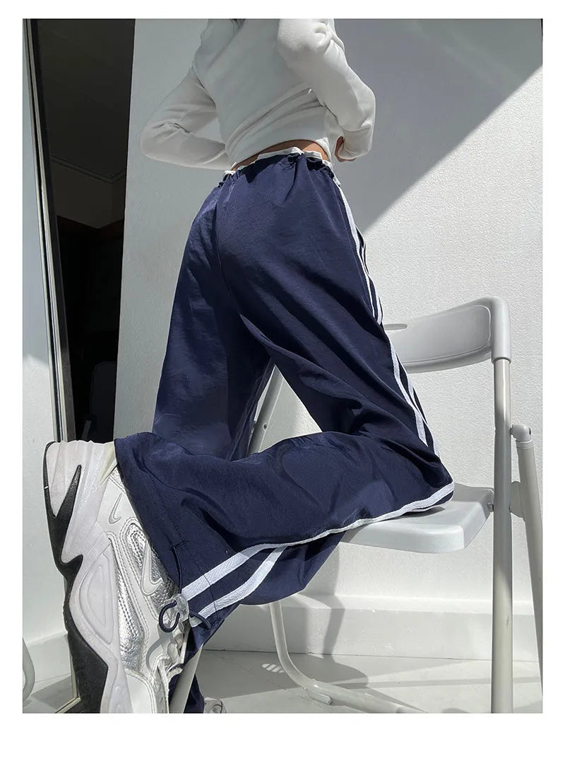 Women's navy blue loose straight-leg trousers with white contrast ribbon detail on parallel bars, low waist, draping silhouette