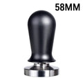 Black manual coffee tamper with stainless steel base and aluminium handle on a coffee station