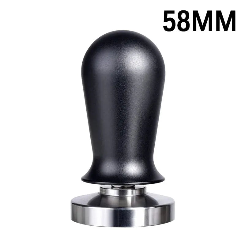 Black manual coffee tamper with stainless steel base and aluminium handle on a coffee station