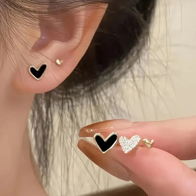 Three pairs of heart shape alloy earrings in gold, black, black white, and pink colours with love design elements