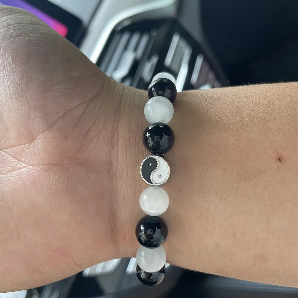 Opal and black agate Tai Chi bracelet with 10mm polished stone beads on a wrist.