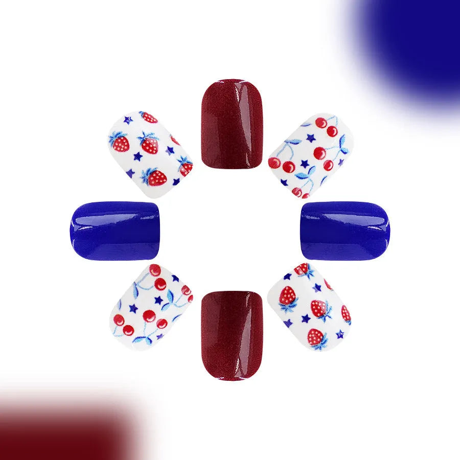 Short glossy red and blue strawberry cherry pattern false nail stickers laid out.