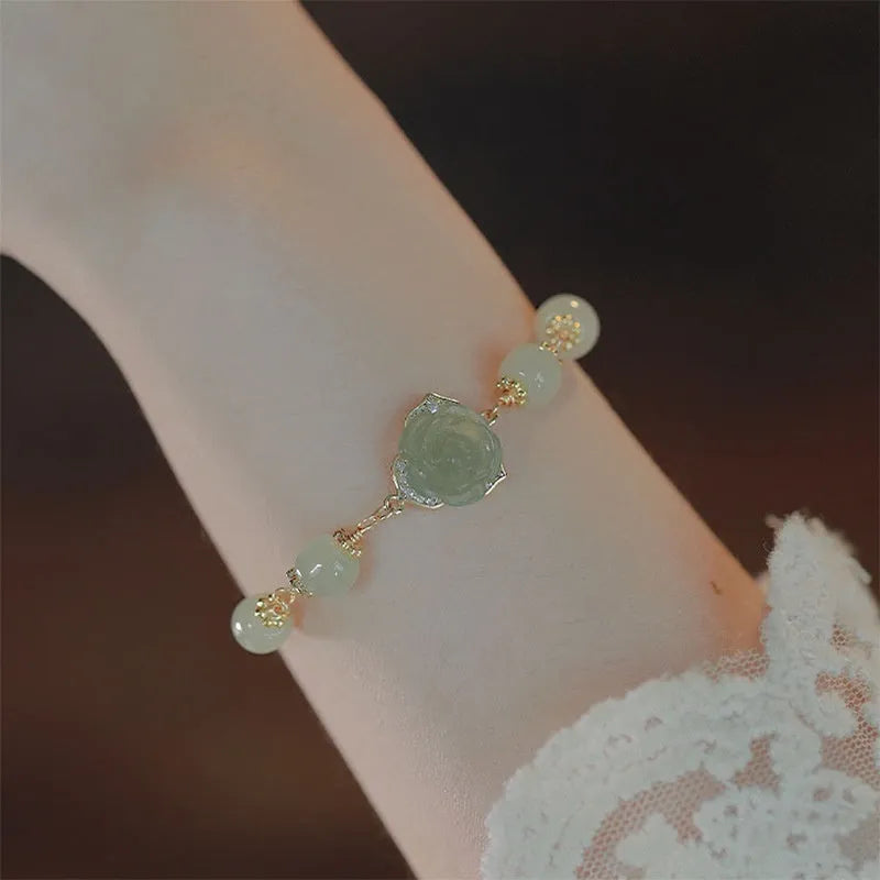 Original design women's bracelet with a Hetian Jade rose and 14K gilded details on a wrist.