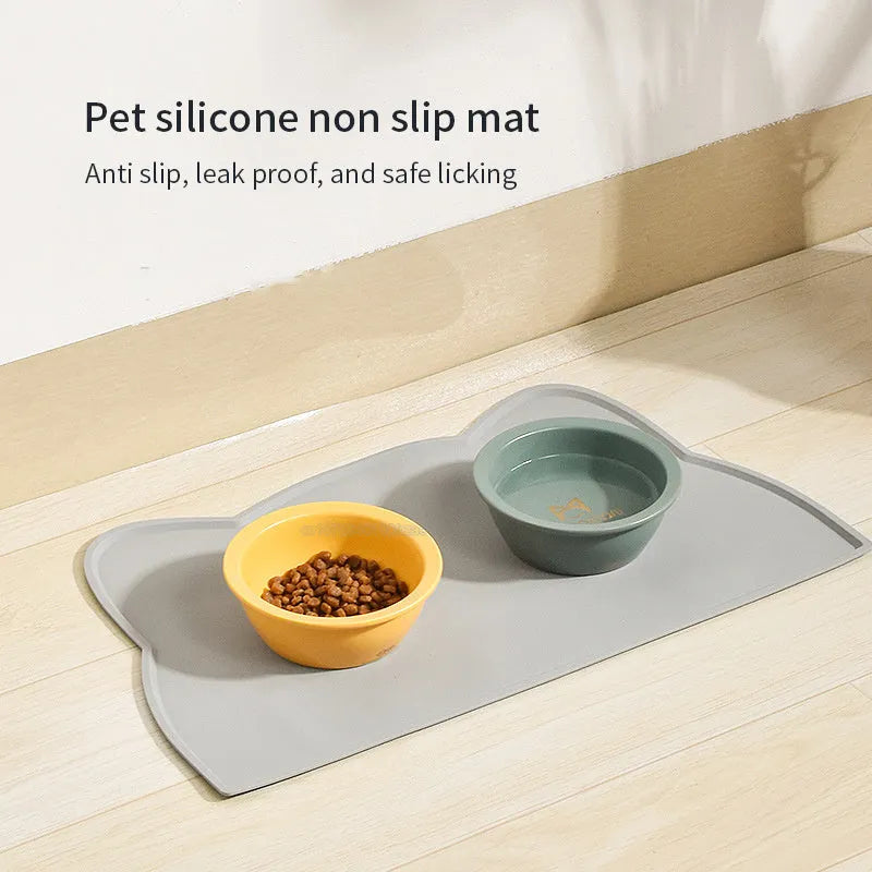 Blue silicone pet feeding mat with cat head shape under food and water bowls