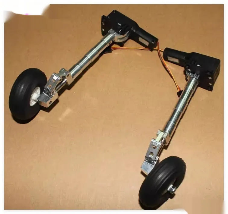 Pair of silver alloy retractable landing gear with shock absorbers and black rubber wheels for RC model aircraft.