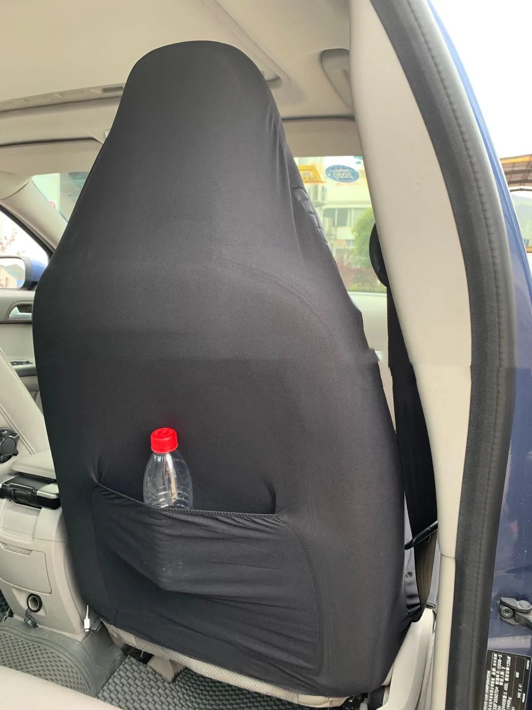 Black quilted car seat cover made of PU and polyester fabric with plastic hooks.