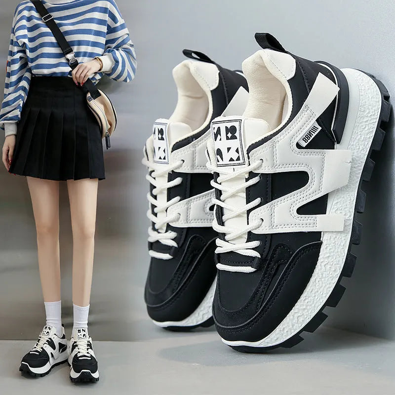 Low-top round-toe sneaker in black or white with lace-up front and flat rubber sole.
