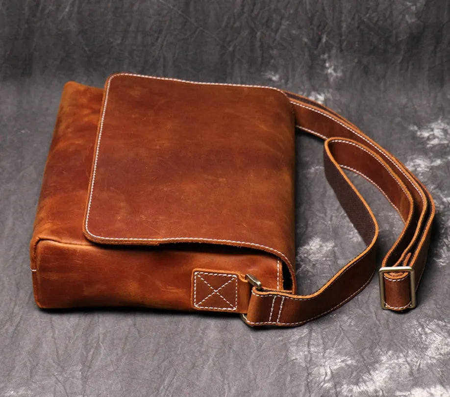 Vintage brown leather mens messenger bag with a flap opening and adjustable shoulder strap.