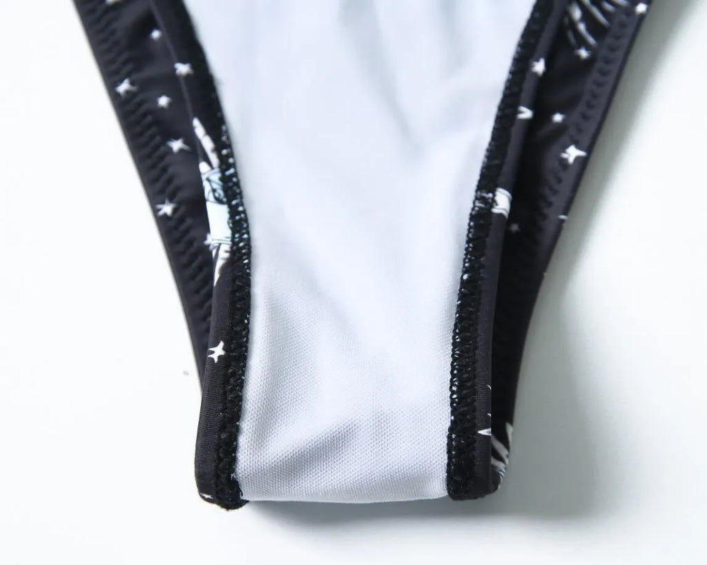 Black bikini print one-piece swimsuit with a split tube top design on a mannequin.