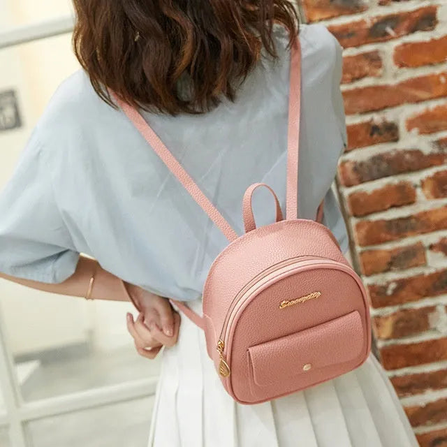 Women's small PU leather backpack shoulder bag in black showing front zipper and compact size