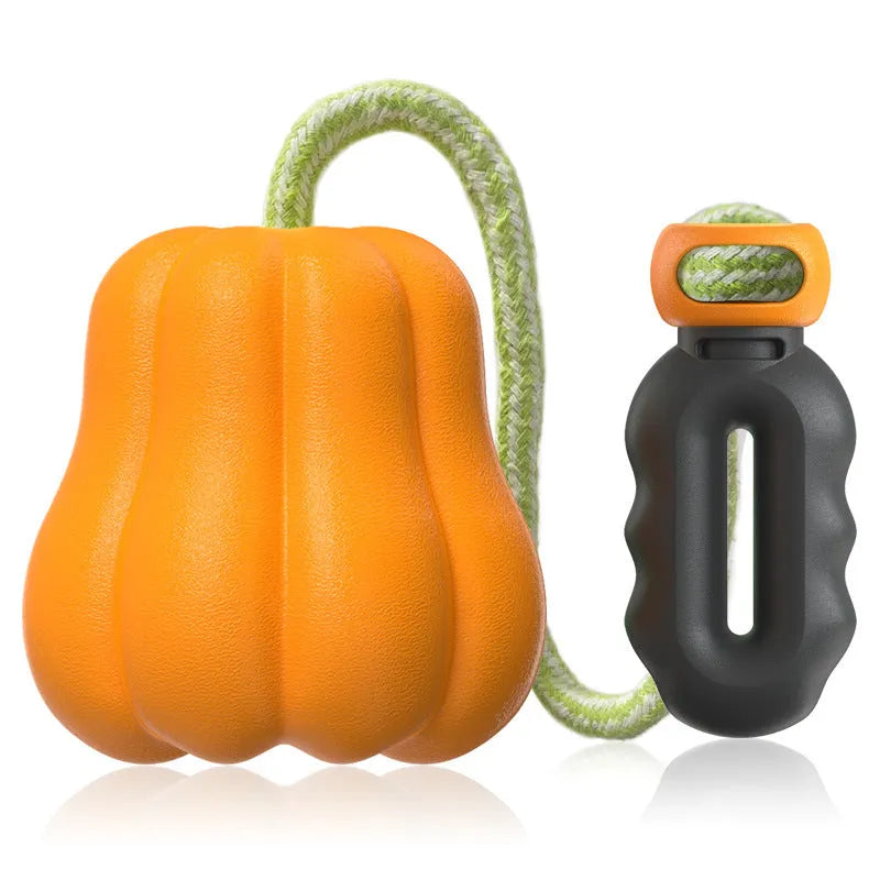 Orange plastic pumpkin dog toy with a bite molar texture and a rope attached for throwing.