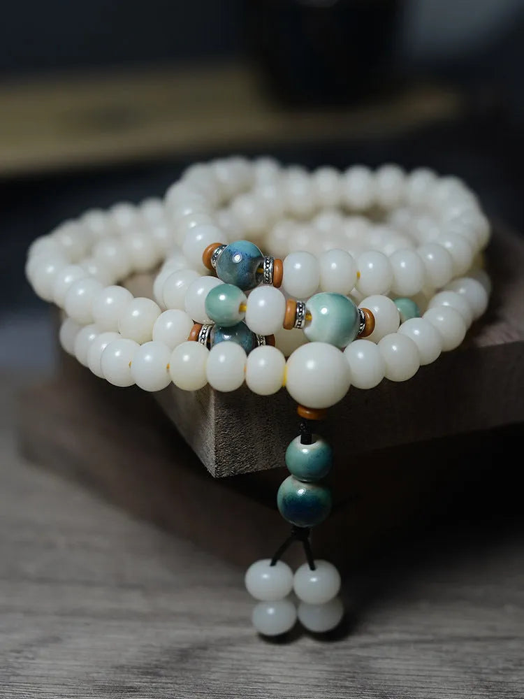 White jade bodhi seed bracelet with 108 flat round beads on a wrist.