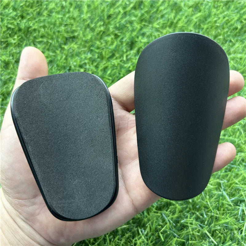 Extra small plastic football shin guards in black and white, measuring 8x5cm