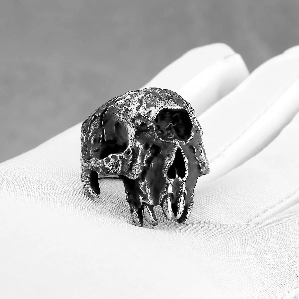Silver-toned alloy ring with a detailed one-eyed skull design on a black background.