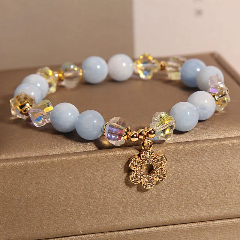 Women's adjustable bracelet with aquamarine crystal four-leaf clover charm and pearl detail.