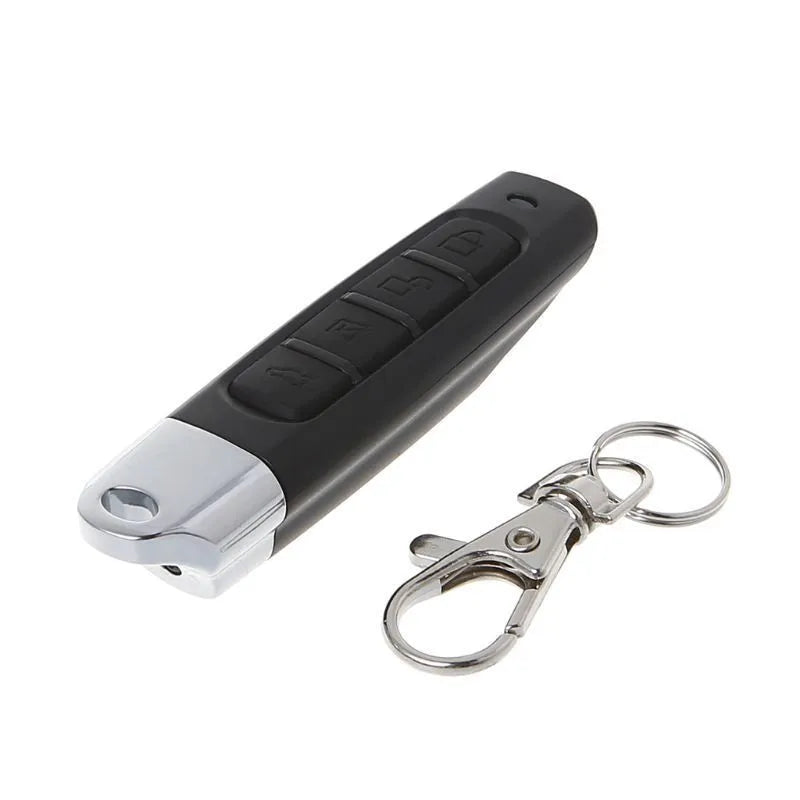 A black rolling door remote control duplicator unit showing its compact size and buttons for copy and test functions.