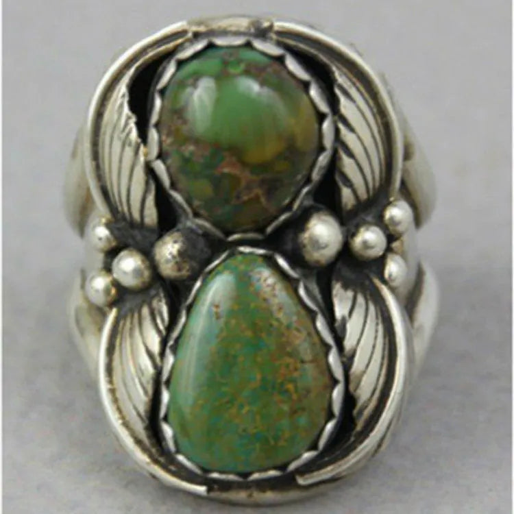 Close-up of a women's turquoise geometric ring with a retro inlaid design on a finger.