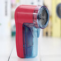 Portable electric clothing lint remover shaver in hand, showing compact size and shaving head.