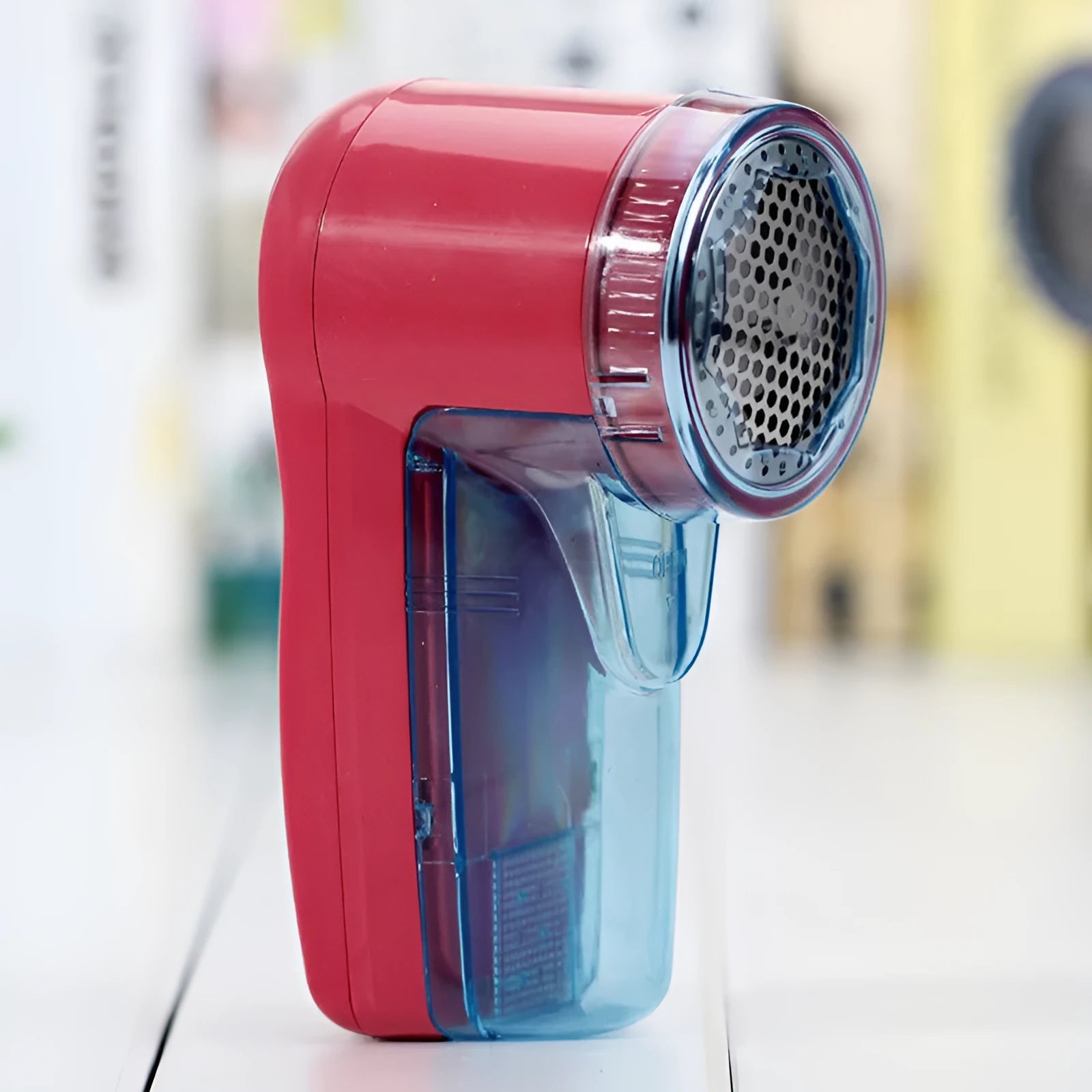 Portable electric clothing lint remover shaver in hand, showing compact size and shaving head.