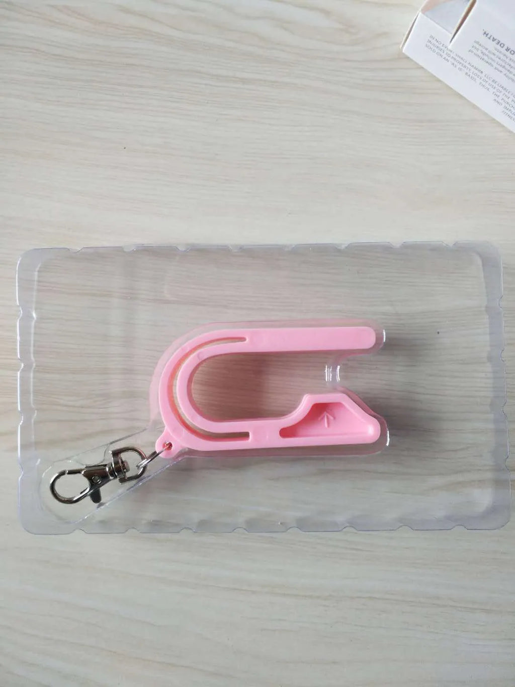 Plastic car seat key for pressing the red button on a child's car seat buckle, shown in pink, violet or green