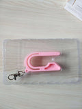 Plastic car seat key for pressing the red button on a child's car seat buckle, shown in pink, violet or green