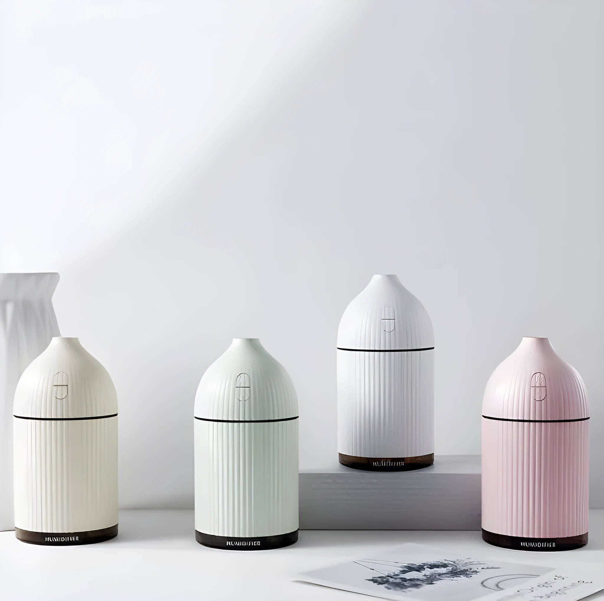 White ultrasonic aromatherapy diffuser humidifier with USB cable and LED light on wooden table
